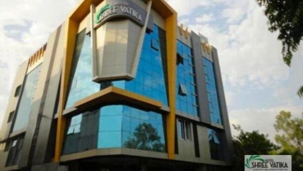 A modern hotel building with a distinctive triangular roof structure and a prominent logo. - Hotel Shree Vatika (Bhopal)