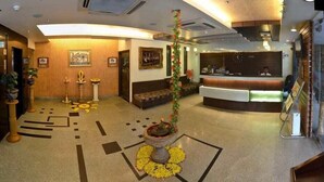 A hotel lobby with a reception desk, seating area, and decorative elements like a central plant and patterned floor design. - Hotel Shree Vatika (Bhopal)