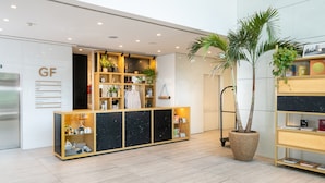 A reception desk with a wooden and black marble design, surrounded by potted plants and shelves with books and decorative items. - INNSiDE by Meliá Milano Torre Galfa (Milan)
