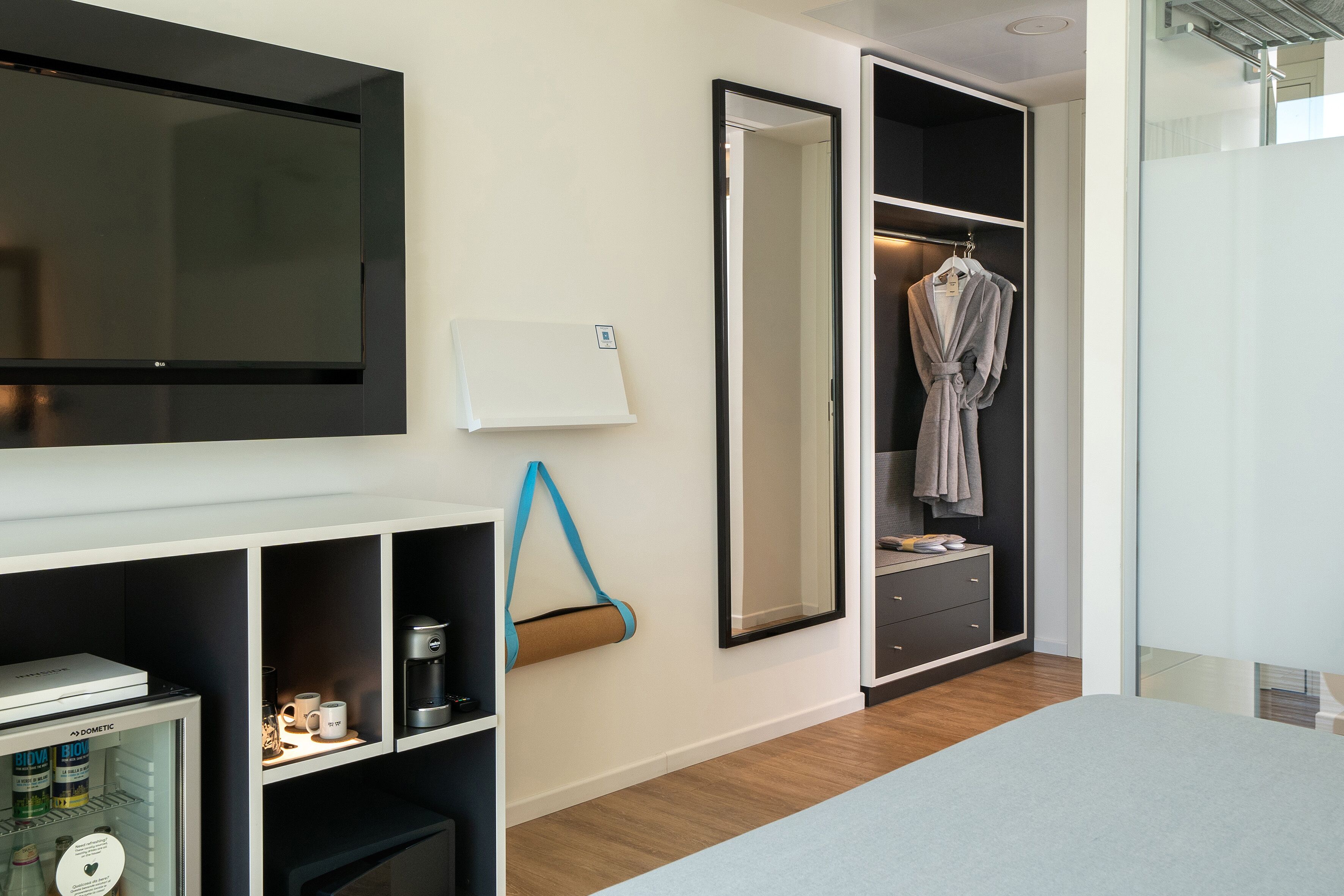 Une chambre moderne équipée d’un téléviseur intégré, d’un mini-réfrigérateur, d’une machine à café et d’une armoire avec un miroir.