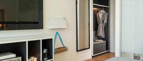 Une chambre moderne équipée d’un téléviseur intégré, d’un mini-réfrigérateur, d’une machine à café et d’une armoire avec un miroir.
