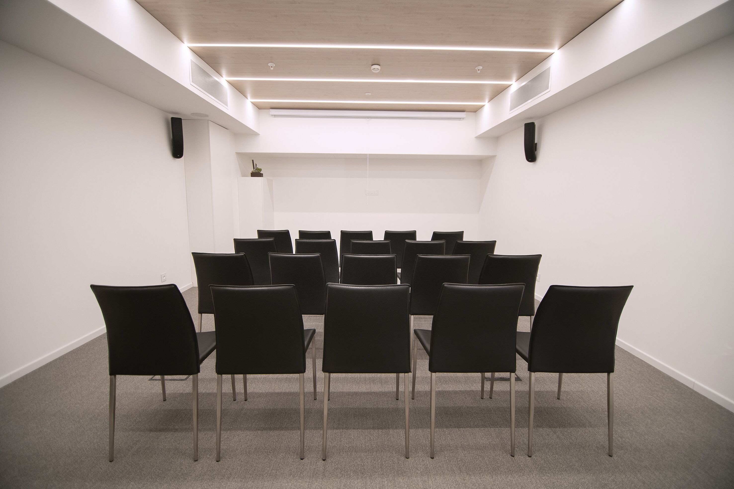 A conference room with a long table and chairs, white walls, and recessed lighting.