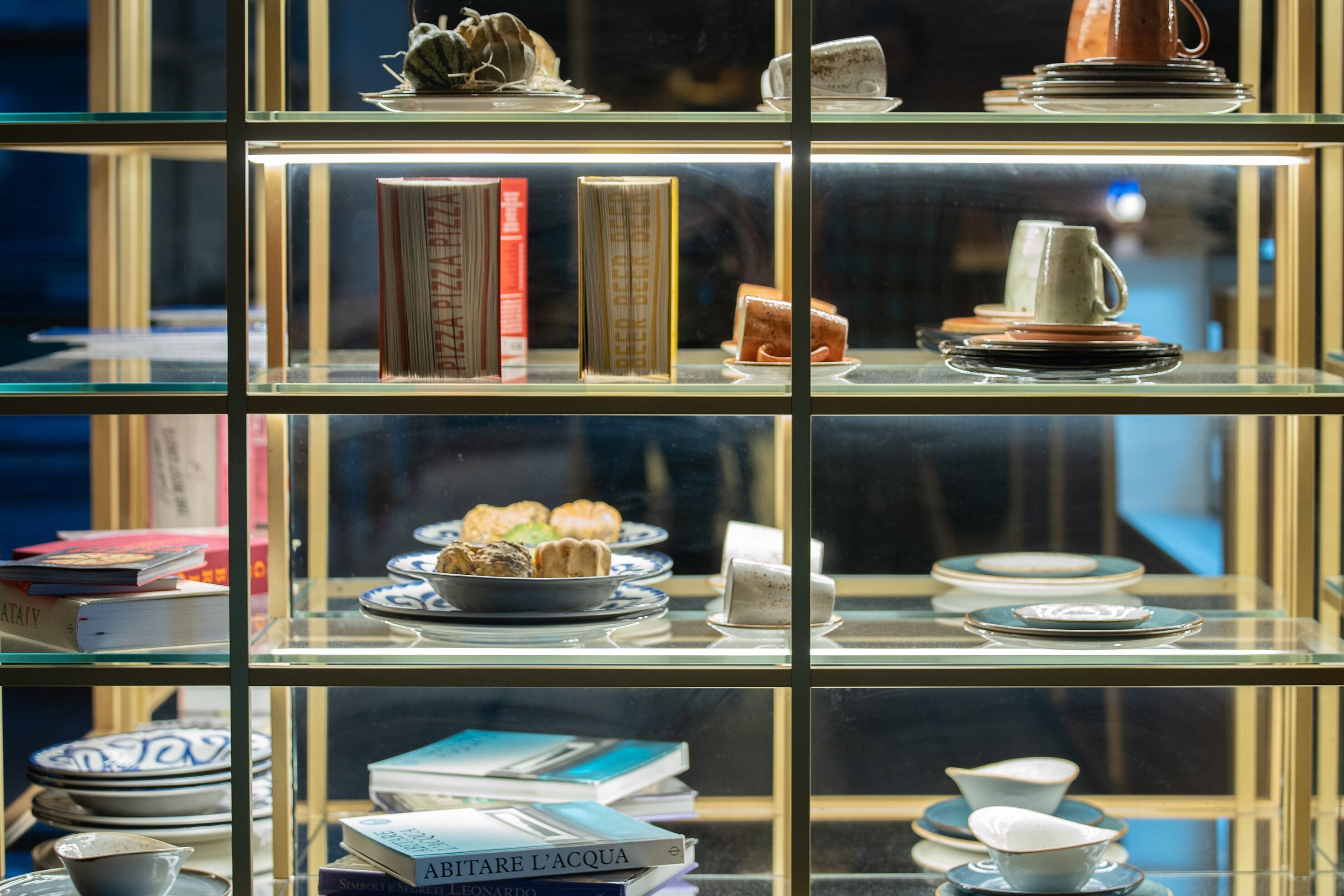 A display of books and ceramics in a glass case.