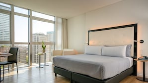 A modern hotel room with a large bed, a desk, and a view of the city through large windows. - INNSiDE by Meliá Milano Torre Galfa (Milan)