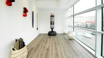 Una habitación moderna con un saco de boxeo, una pelota de ejercicios y una cesta tejida.