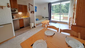 Una cocina compacta con comedor, sofá y un amplio ventanal.