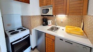 Cocina compacta equipada con estufa, microondas, pileta y lavavajillas.