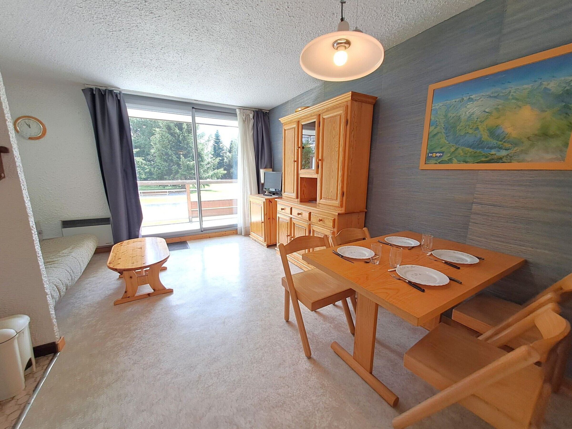 A dining area with a wooden table and chairs, a cabinet, and a painting on the wall.