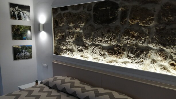 A bedroom with a bed, a wall-mounted aquarium, and three framed pictures. - B&B Ninfa (Caserta)
