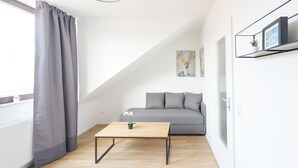 Ein modernes Wohnzimmer mit einem grauen Sofa, einem Holztisch und einem grauen Vorhang.