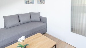 Ein modernes Wohnzimmer mit einem grauen Sofa, einem Holztisch und zwei an der Wand befestigten Bildern von Hirschen.