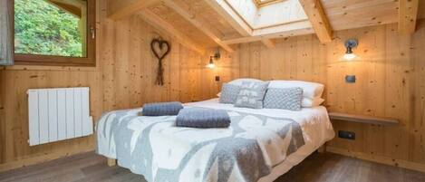 Un dormitorio rústico de cabaña de madera con cama, tragaluz y una decoración con forma de corazón en la pared.