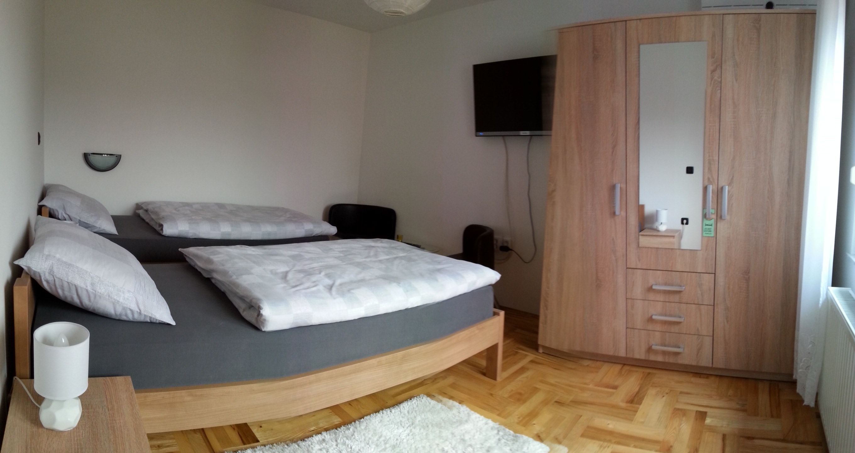 Un dormitorio con cama, armario, televisor y mesita de noche.