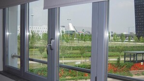 Ein Fenster mit Blick auf ein modernes Gebäude und eine Grünanlage.