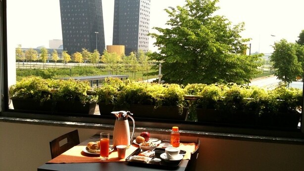 Ein Tisch mit Frühstücksangeboten und Blick auf eine Stadtlandschaft durch ein Fenster.