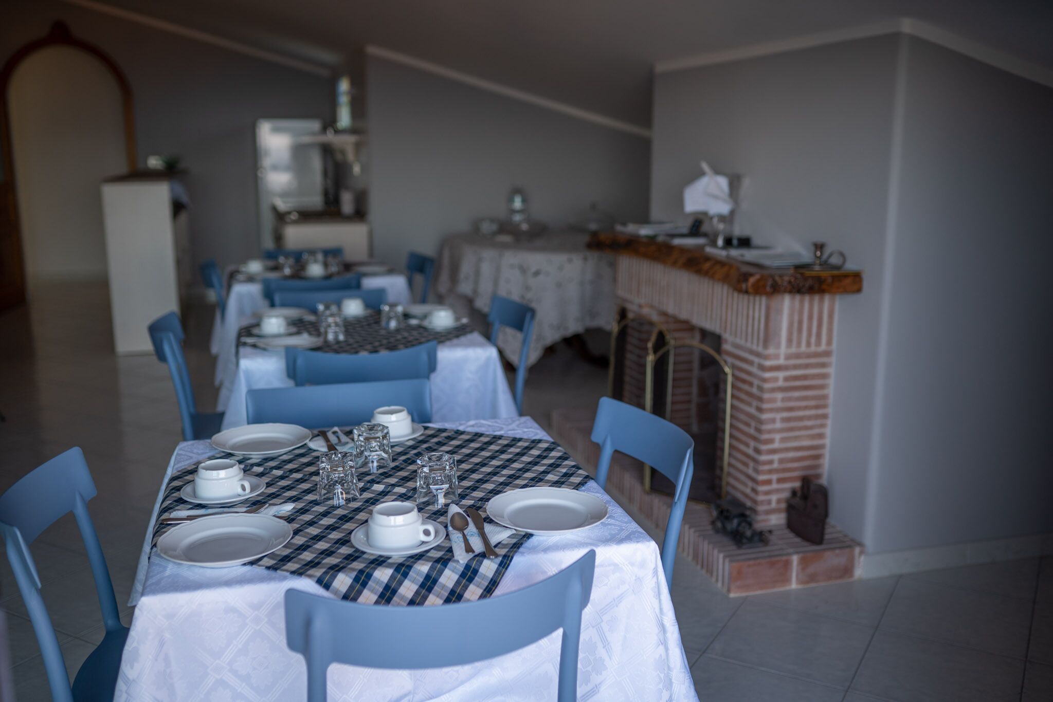 A dining area with a checkered tablecloth, white plates, and blue chairs.