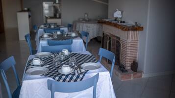 A dining area with a checkered tablecloth, white plates, and blue chairs.