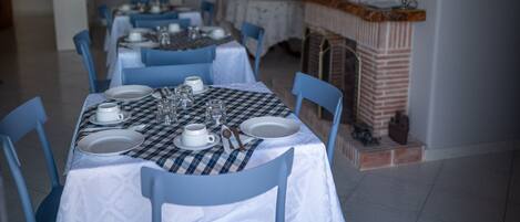 A dining area with a checkered tablecloth, white plates, and blue chairs.