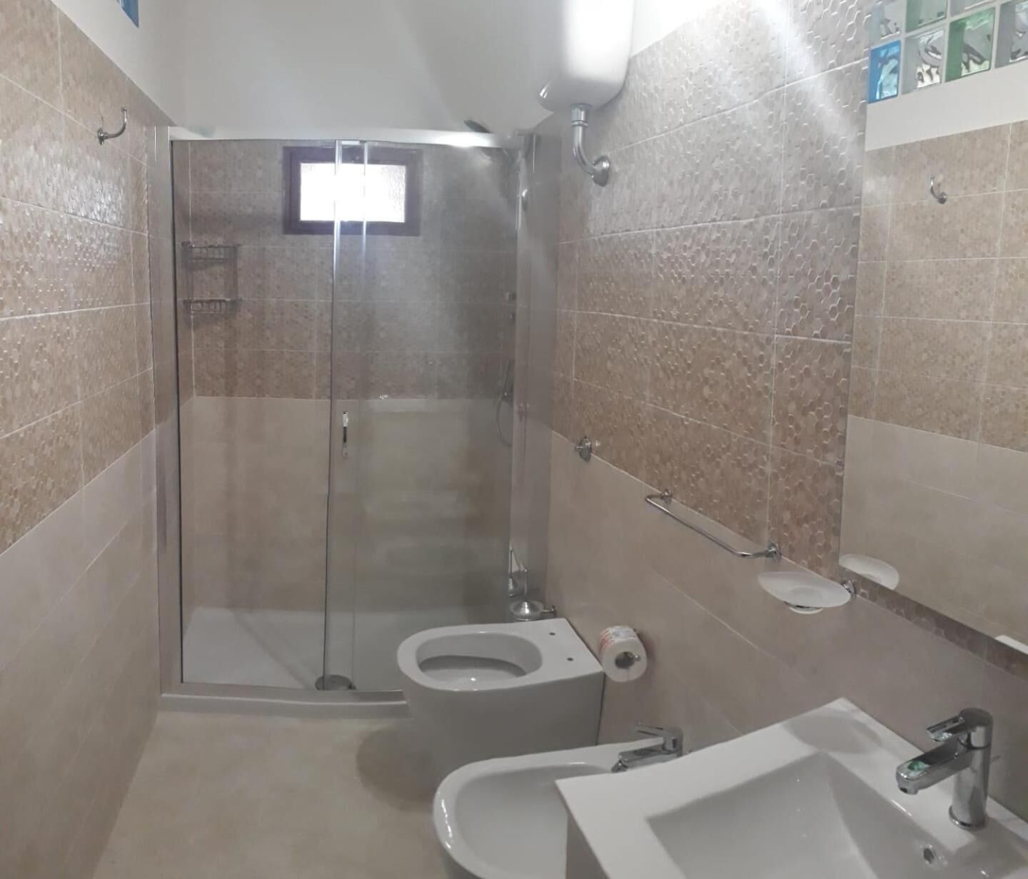 A small, modern bathroom with a glass shower enclosure, a toilet, and a sink.