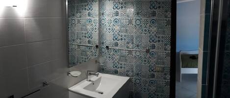 Une salle de bain avec un lavabo blanc, un miroir et des carreaux décoratifs sur les murs.