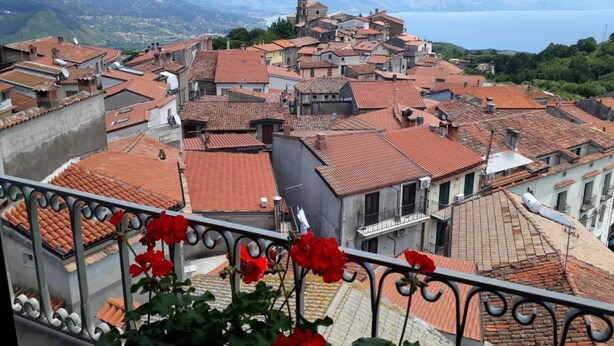 A view of a town with red-tiled roofs and a mountainous backdrop.