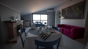A dining area with a table set for four, a red sofa, and a large window.