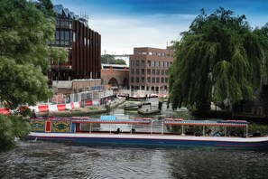 Un canal con una barca, edificios y árboles.