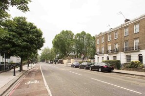 A street lined with parked cars and trees, with a clear road and a designated bike lane. - Camden Street NW1 - Camden Town, Camden Road (London)