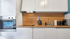 A modern kitchen with white cabinets, a wooden countertop, a built-in oven, a coffee maker, and a toaster. - Camden Street NW1 - 🚇 Camden Town 🚇 Camden Road (London)