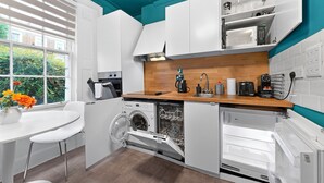 A compact kitchen with a washing machine, a coffee maker, and a microwave. - Camden Street NW1 - 🚇 Camden Town 🚇 Camden Road (London)