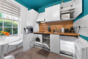 Een kleine keuken met een wasmachine, een koffiezetapparaat en een magnetron.