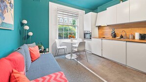 A compact living space with a kitchenette, a dining area, and a sofa with cushions. - Camden Street NW1 - Camden Town, Camden Road (London)