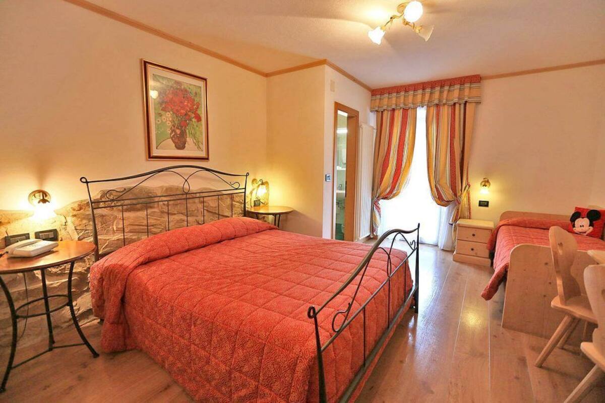 Ein Schlafzimmer mit Bett, Nachttisch, Lampe und Stuhl.