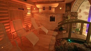 Een wellnessruimte met houten wanden, een stenen muur met open haard en een klein waterpartij.