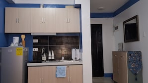 Una cocina compacta con armarios de madera clara, estufa integrada y refrigerador.