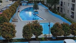 Un edificio residencial con piscina, coches aparcados y cielo despejado.