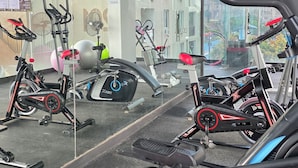 Un gimnasio con equipo de ejercicio variado, incluyendo cintas de correr y bicicletas estáticas, y un espejo grande que refleja la sala.