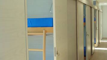 A room with a bunk bed, a ladder, and a wardrobe with mirrored doors.