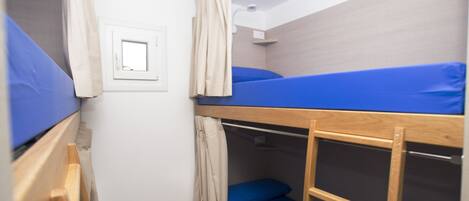 Dormitorio con literas, ventana, cortinas y escalera de madera.