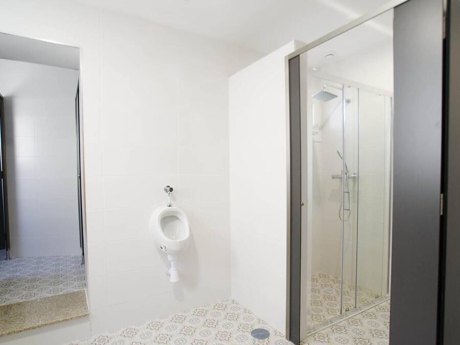 Un baño moderno con orinal, ducha y baldosas de suelo estampadas.