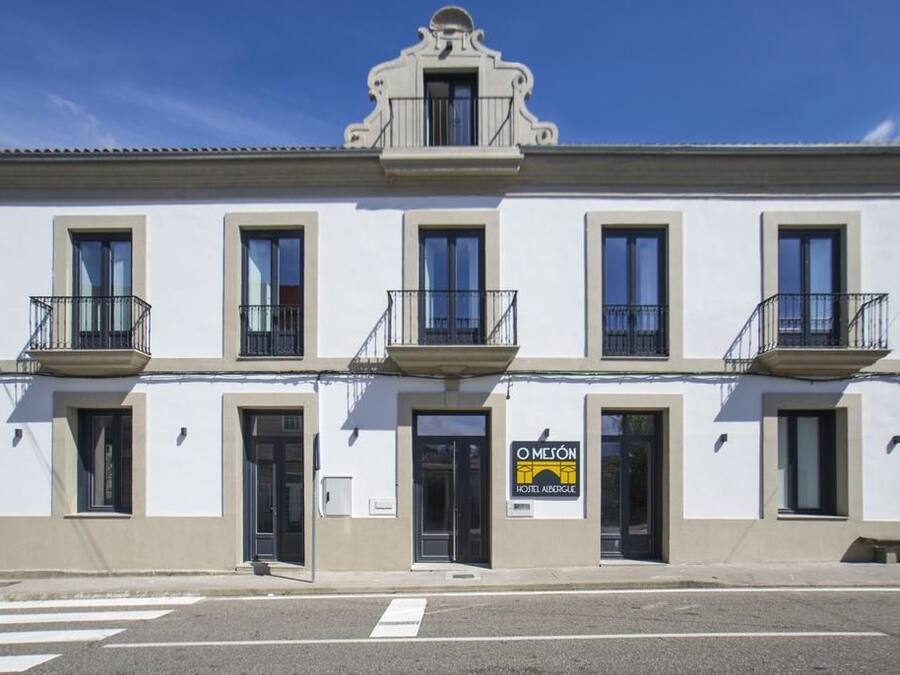 A two-story building with a sign for 'O Mesón Hostel Auberge'.