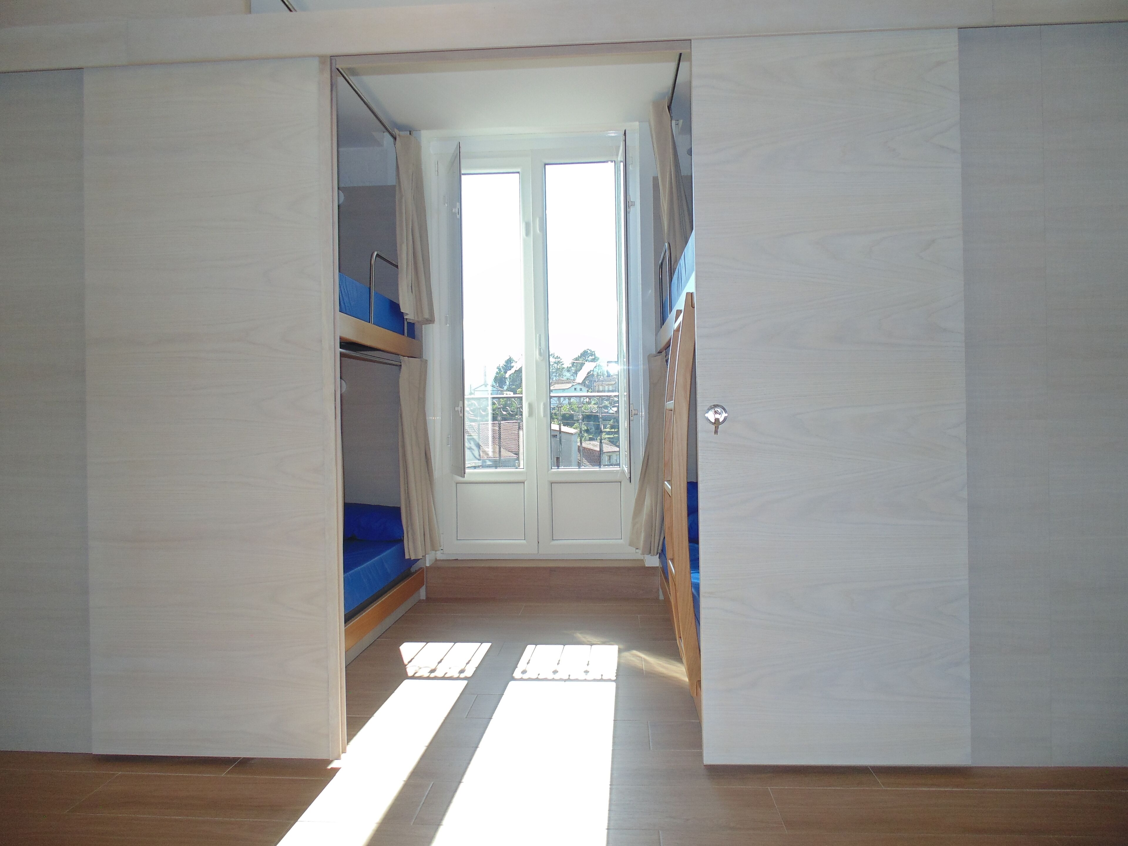 Ein Zimmer mit Etagenbett, einer Schiebetür und Blick auf Gebäude.