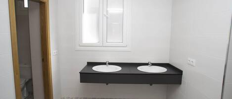 A bathroom with two sinks, a window, and patterned floor tiles.