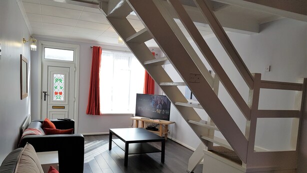 Un salon avec un canapé, une table basse, un téléviseur et un escalier.