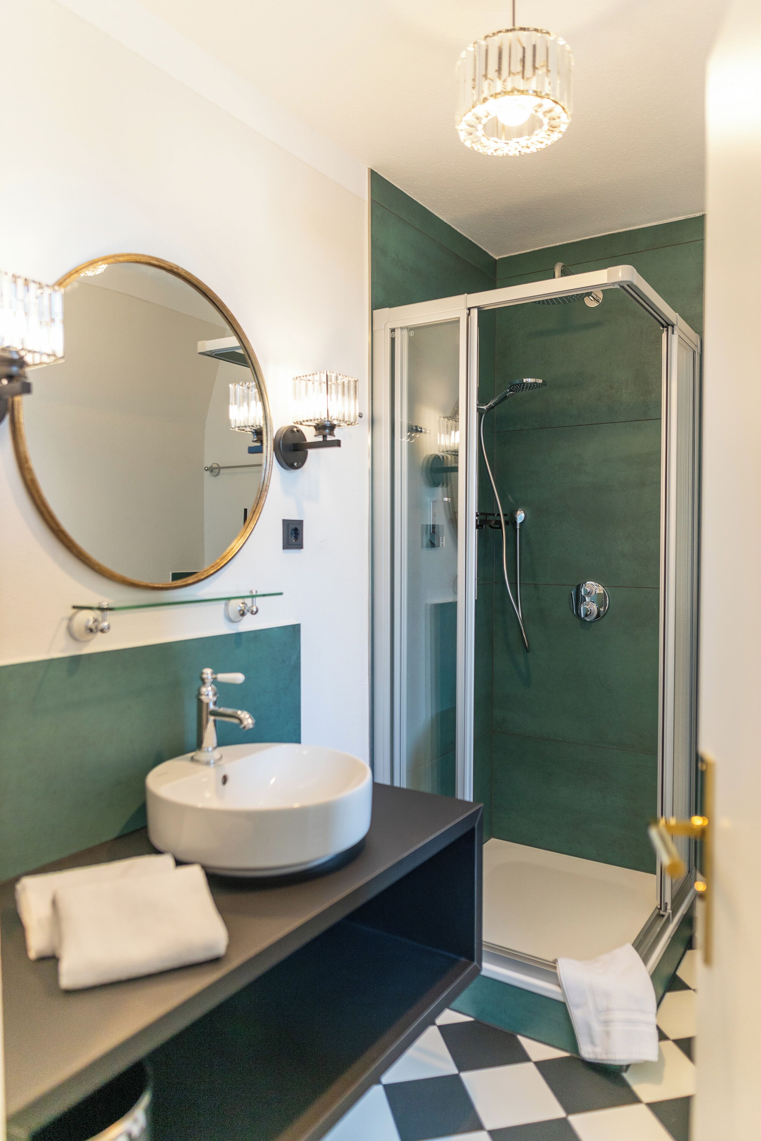 Un baño con un espejo redondo, un lavamanos y una ducha.