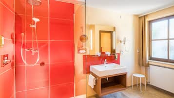 A modern bathroom with a glass-enclosed shower, a white sink, and a large mirror.