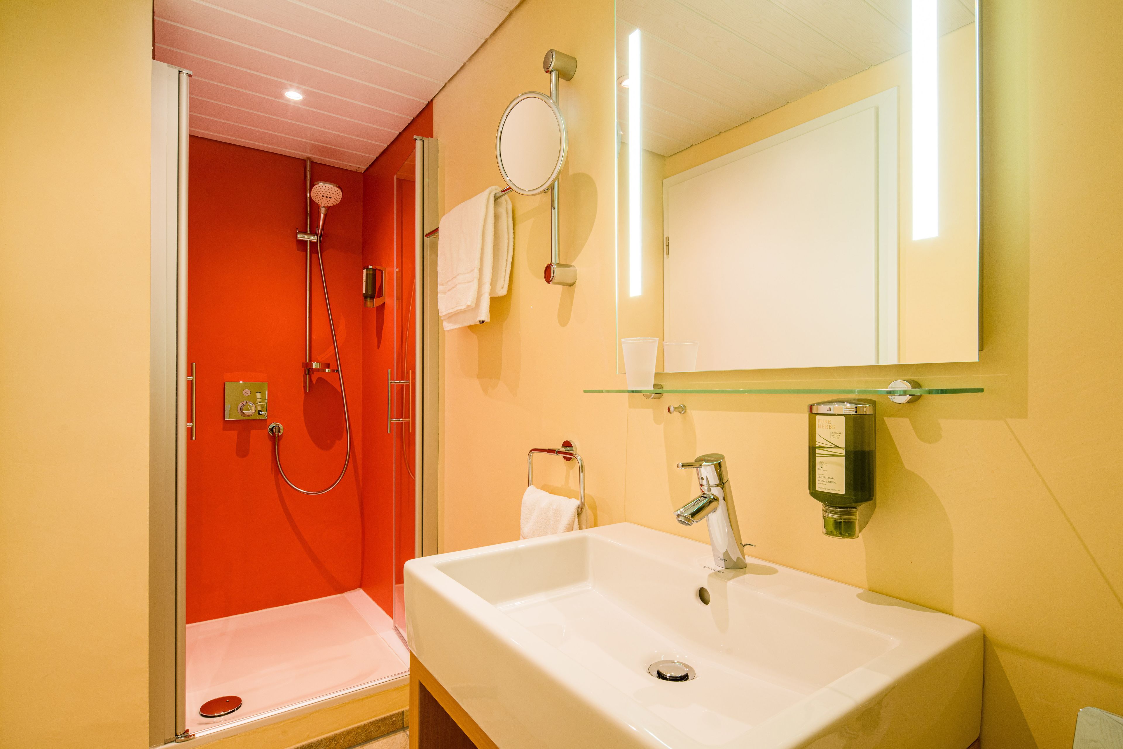 Un baño con lavamanos blanco, cabina de ducha de vidrio y espejo.
