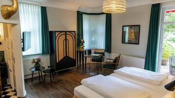 Une chambre d’hôtel comprenant un lit, un bureau, une chaise, une petite table et un objet décoratif accroché au mur.