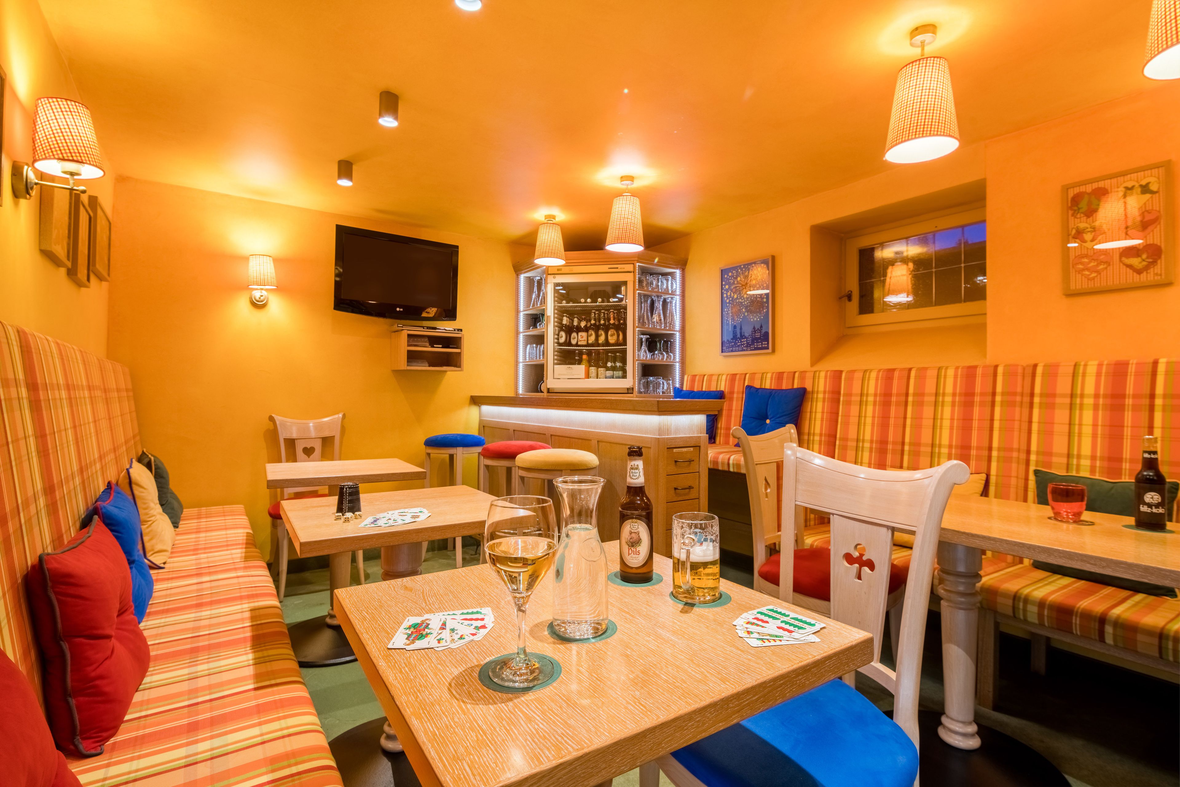 A cozy restaurant with striped seating, a bar area, and a television mounted on the wall.