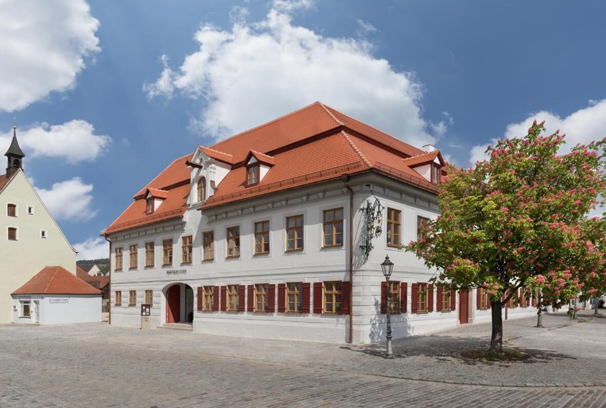 Ein historisches Gebäude mit rotem Ziegeldach und einem zentralen Rundbogenportal.